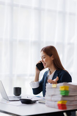 Asian businesswoman talking on phone, using laptop, looking at screen, entrepreneur manager consulting client by call, looking at computer screen, discussing project, reading information