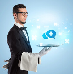 Handsome young waiter in tuxedo holding healthcare icons on tray