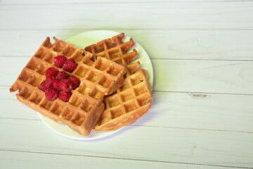 Top view on fresh fried viennese waffles with raspberries lay on white plate . Copy space for text, flat lay, top view