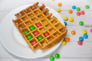 Kids food. Funny creative breakfast. Blgian waffles and colorful chocolate round candies. Selective focus