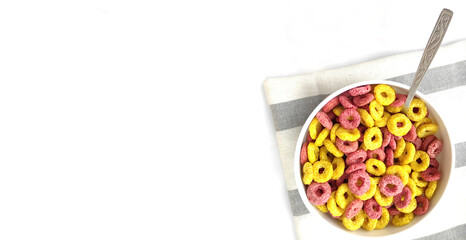 Good morning. Light quick breakfast. Multicolored cereals with milk close-up on a napkin with a spoon on a white background. Fast breakfast for kids. 