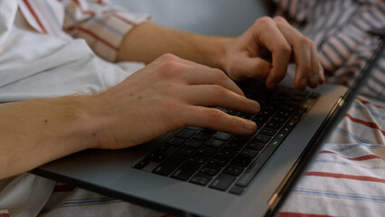 Fototapeta na wymiar Freelancer hands typing laptop keyboard in pajamas closeup. Man working late