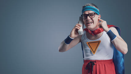 Funny superhero making a phone call using a cordless telephone