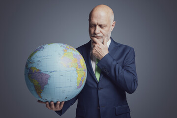 Business executive holding a globe and thinking