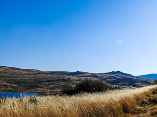 Landscape at Serra da Estrela, Portugal. Mountains, blue skies and lake, and golden grass. Sunny day.