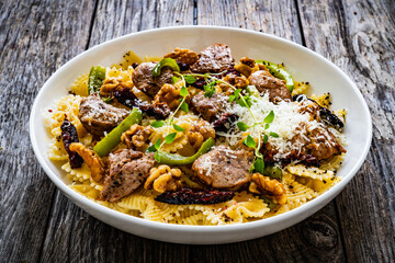 Farfalle with roasted pork loin, sauce, parmesan cheese, nuts and  green bell pepper served on wooden table
