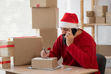 Indian Santa online business owner accepts an order over the phone, writing an order, ordering a customer gifts. Small business Christmas sale.