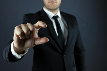 A businessman on a black background shows a gesture with two fingers, small, holding. Works on an...
