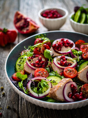 Tasty salad - roast pork loin, cucumber, cherry tomatoes, pomegranate, strawberries and fresh, green vegetables on wooden table
