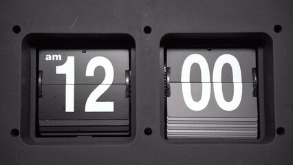 A flip clock changing from 11:59 to 12:00 at midnight