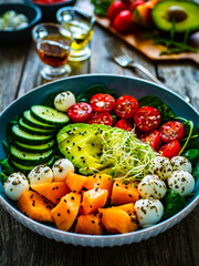 Fresh salad - mozzarella, melon and vegetables on wooden table
