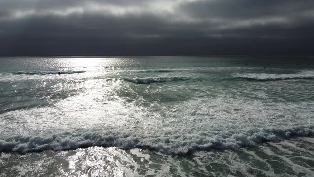 A UAV Aerial View Looking at the a Sultry Cloudy Surf Day at La Jolla Shores as the Sun Sets and Reflects on the Water