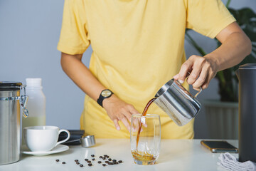 person using pitcher Pour brewed coffee and brew cold black coffee on a mug with roasted Arabica...