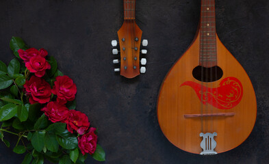 Fototapeta premium Mandolin - a stringed plucked musical instrument and a beautiful red roses
