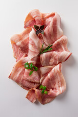 Raw bacon, sliced, with micro greenery and spices, on a white background, close-up,