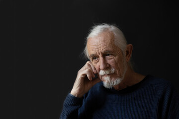 Low key studio portrait of sad beautiful gray hair old man. 