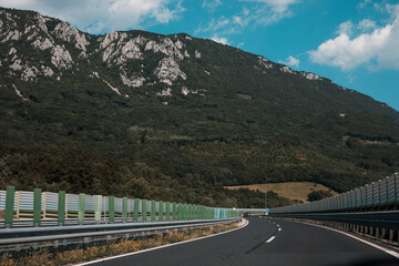 Obraz premium Beautiful scenic landscape on mountains covered with forests. View from the car window on a modern and high-quality highway.