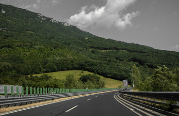 Beautiful scenic landscape on mountains covered with forests. View from the car window on a modern and high-quality highway.