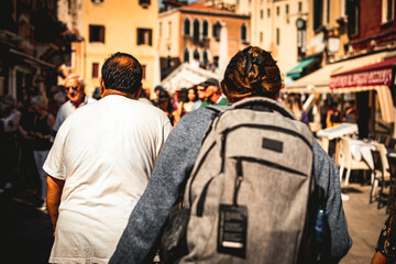 Obraz premium Rear view of a group of people walking the streets of a European city. Tourist with a backpack on a tour.