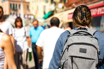 Rear view of a group of people walking the streets of a European city. Tourist with a backpack on a tour.