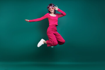 Cheerful young woman jumping against green background