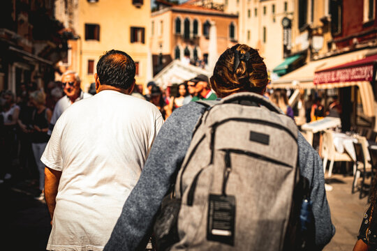 Rear view of a group of people walking the streets of a European city. Tourist with a backpack on a tour.