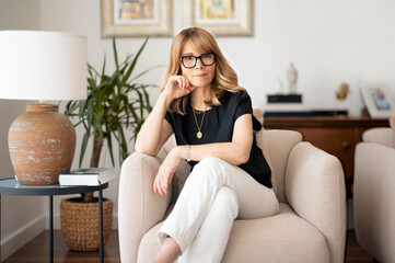 Portrait of thinking mature woman relaxing in armchair at home