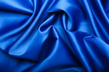 blue silk forming elegant waves with shadows and chiaroscuro, background of textile material
