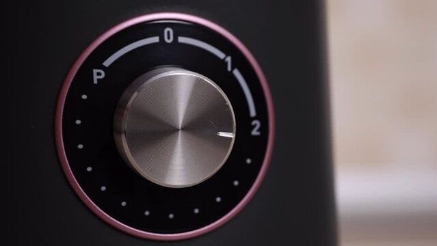 Turning On And Off A Kitchen Blender. Close-up. The Hand Rotates The Metal Button Of The Blender. Electrical Appliance With Power Adjustment.