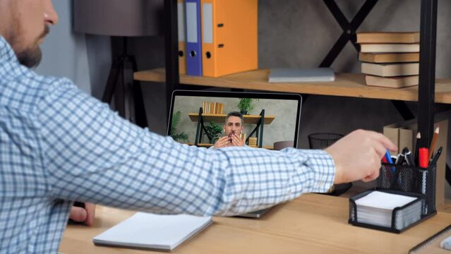 Online business meeting. Businessman in laptop screen tells says tasks top manager company. Man employee at home office listen CEO director remote video call webcam chat computer, writes in notebook