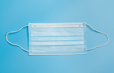 Medical mask. Blue medical mask with a white elastic band, isolated on a blue background.