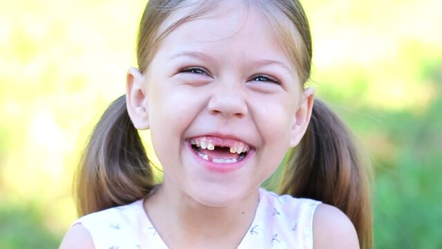 Portrait of laughing and happy toothless caucasian little girl of 6 years looking at camera outdoor summer