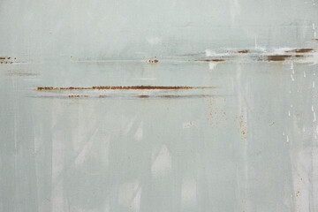 Fragment of an old iron sheet of pale green color. Brush marks are visible. The paint layer has horizontal scratches covered with rust. Background. Texture.