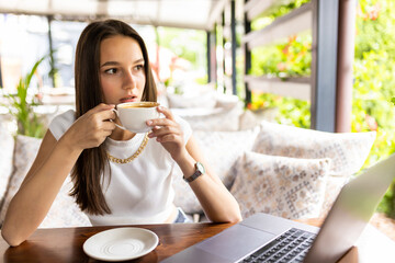 Young woman studying on laptop and enjoying coffee
