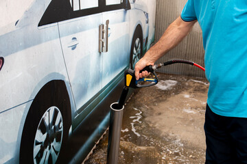 Car washing.  Mature man cleaning automobile with high water pressure. Self service