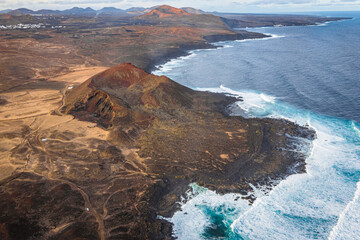 aerial view on volcano and mountains on coast with ocean waves on lanzarote