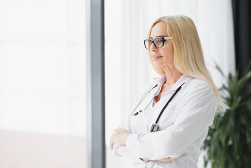 Successful mature caucasian senior female doctor in white coat at hospital.