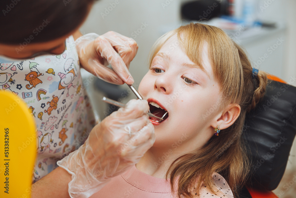 Wall mural the dentist performs an examination procedure on a cute little girl. Little girl sitting in the dentist's office