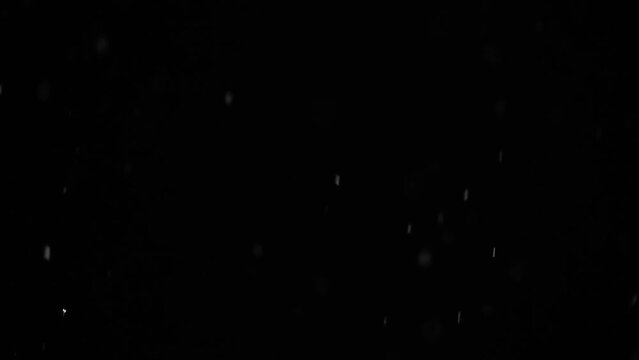 Bokeh of white snow hd slow motion video on a black background. Falling snowflakes on night sky background, isolated for post production and overlay in graphic editor.