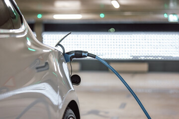 Electric car charger plugged in a vehicle socket in the parking garage