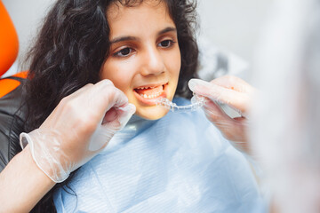teen girl holding braces, dentist puts braces on girl. dental care and orthodontic concept.