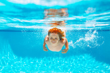 Child underwater swim in the swimming pool. Cute kid boy swimming in pool under water.