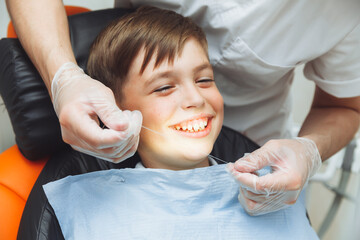 the dentist brushes the boy's teeth with dental floss. oral hygiene in children. pediatric...