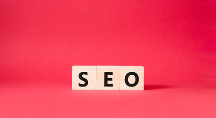 Seo symbol. Wooden blocks with words 'Seo'. Beautiful red background. Business and seo concept. Copy space.