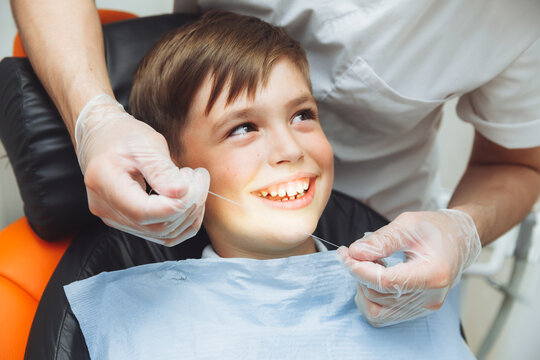 the dentist brushes the boy's teeth with dental floss. oral hygiene in children. pediatric dentistry. flossing your teeth.