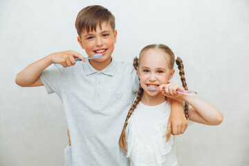 Children, a boy and a girl brush their teeth and laugh, isolated on a white background. pediatric dentistry. hygiene and cleaning of teeth