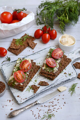 vertical composition. Appetizing rye toasts with tomatoes, cheese and dill on a light board. View from above