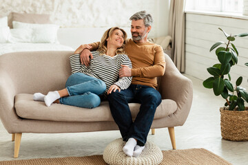 Happy Middle Aged Couple Hugging Relaxing On Sofa At Home