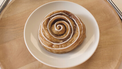 Close up of sweet bun snail spinning slowly on wooden tray background, cooking homemade pastries....