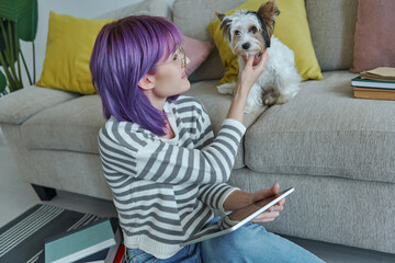 Cheerful teenage girl spending time with her little dog at home